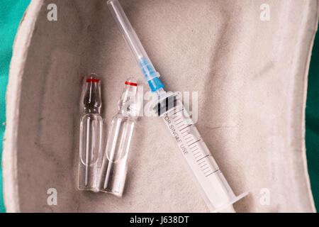 Medizinische Spritze und Fläschchen liegen in einer verwenden Kapsel auf grünem Hintergrund des Krankenhauses. Hintergrund kann eine Textile gehören ein Arzt oder Krankenschwester w Stockfoto