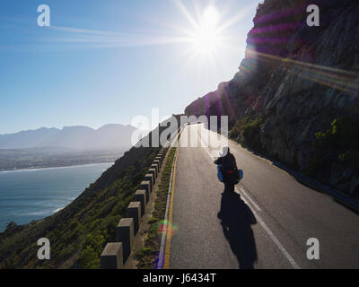 Paar Motorrad an sonnigen Straße entlang Ozean Stockfoto