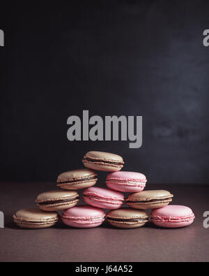 Pyramide von Schokolade und Himbeeren pastellfarbenen Macarons oder Makronen auf dunklem Hintergrund Stockfoto