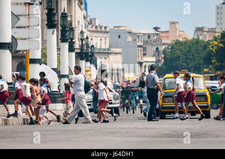 Havanna - ca. Juni 2011: Eine Gruppe von kubanischen Schulkinder in Uniform überqueren Sie die Straße vor einem typischen Lineup von alten russischen und amerikanischen Autos. Stockfoto