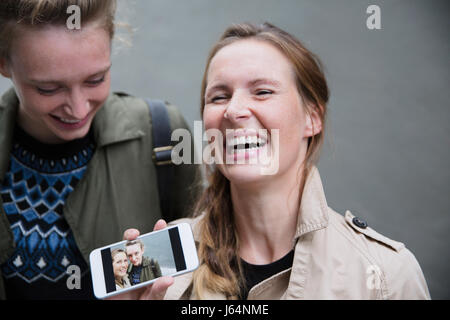 Junge Frauen zeigen Selfie Foto auf smart Phone lachen Stockfoto