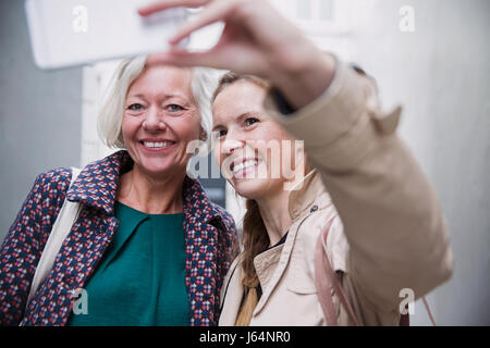 Lächelnde Mutter und Tochter nehmen Selfie mit Kamera-Handy Stockfoto
