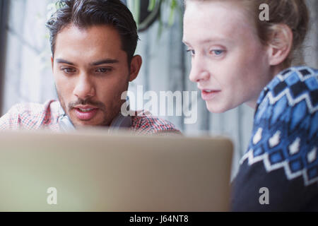 Ernster junger Mann und Frau mit Laptop im café Stockfoto