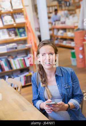 Porträt lachende schwangere Frau mit Handy im shop Stockfoto