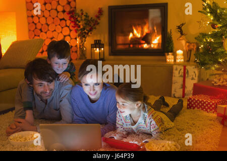 Familie Essen Popcorn und Viedeo auf Laptop in ambient Weihnachten-Wohnzimmer mit Kamin Stockfoto