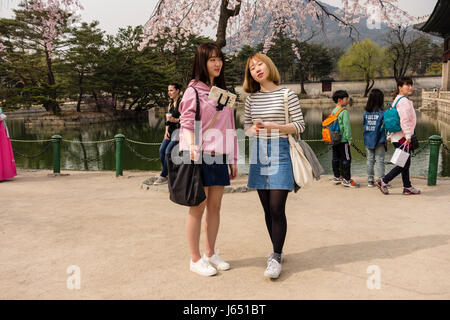 Zwei junge Frauen nehmen Selfies mit einem Mobiltelefon & Selfie kleben im Gyeongbokgung Palace. Seoul, Südkorea Stockfoto