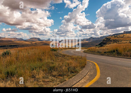 Gebogene leer ländlichen Asphaltstraße durch trockenen Winter Berglandschaft gegen blauen Wolke Himmel Horizont n Orange Free State in Südafrika Stockfoto