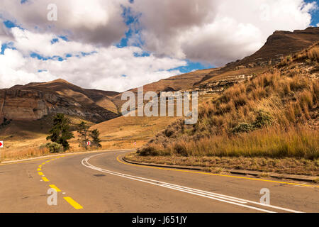 Gebogene leer ländlichen Asphaltstraße durch trockenen Winter Berglandschaft gegen blauen Wolke Himmel Horizont n Orange Free State in Südafrika Stockfoto