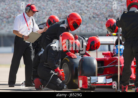 Manager mit Stoppuhr Pit Crew Austausch Formel-1 rennen Auto Reifen in der Boxengasse Stockfoto