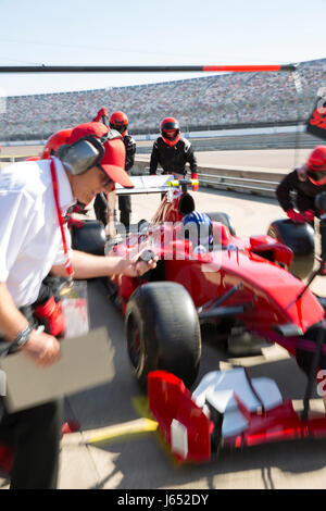 Manager mit Stoppuhr Pit Crew Ersetzen von Reifen auf Formel 1 Rennwagen in der Praxis Sitzung Pit Lane Stockfoto