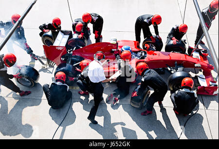 Manager mit Stoppuhr Pit Crew Ersetzen von Reifen auf Formel 1 Rennwagen in der Boxengasse Stockfoto