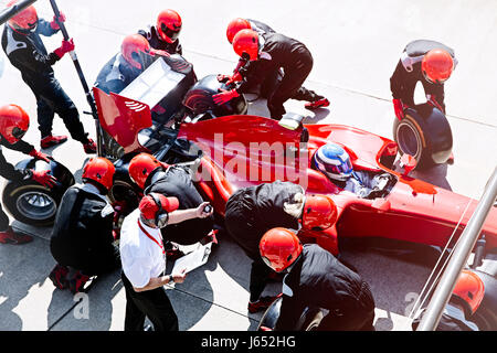 Manager mit Stoppuhr Pit Crew Ersetzen von Reifen in der Boxengasse Stockfoto