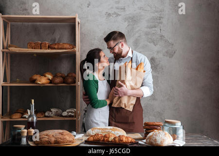 Bild von glücklich liebende Paar Bäcker Brot in den Händen halten und einander betrachtend. Stockfoto