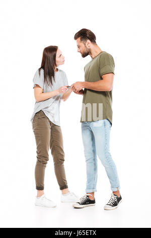 Bild von wütenden jungen Liebespaar stehend isoliert auf weißem Hintergrund. Auf der Suche nach beiseite und Telefon halten. Stockfoto