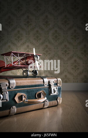 Koffer auf dem Boden mit Karten und Spielzeug aus Holz Flugzeug. Stockfoto