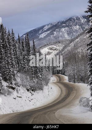 Autobahn durch Schnee bedeckt Wald, Alaska Highway, Northern Rockies Regional Municipality, Britisch-Kolumbien, Kanada Stockfoto