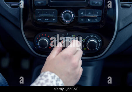 männliche Hand Drücken des Knopfes in modernen Autos. Man passt die Temperatur der Klimaanlage Auto Stockfoto