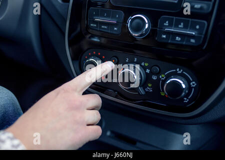 männliche Hand Drücken des Knopfes in modernen Autos. Man passt die Temperatur der Klimaanlage Auto Stockfoto