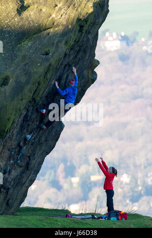 Spotting: Zwei Kletterer Bouldern auf das Kalb bei der Kuh und Kalb Felsen, Ilkley, West Yorkshire, England, UK Stockfoto