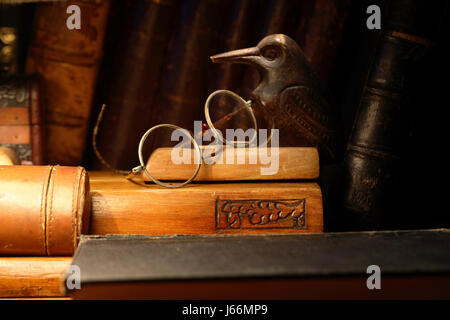 Vintage Stillleben mit der alten Brille auf Schreibtischset gegen Bücher Stockfoto