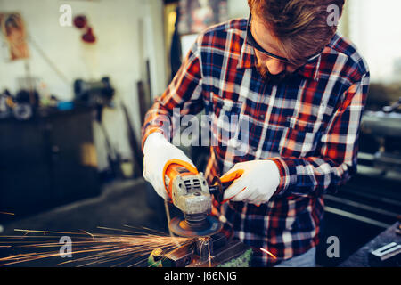 Junge Arbeiter arbeiten mit Mahlwerk Stockfoto