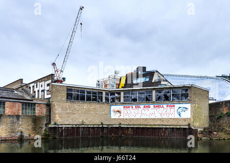 "Ron's Aal und Shell Fish", eine gemalte Zeichen, die sich auf einem lokalen Geschäft an der Fassade ein verfallenes Lagerhaus auf der Regent's Canal, Shoreditch, London, UK Stockfoto