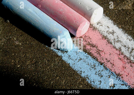 Drei farbige Kreide weiß, rot, blau und das Muster der Streifen auf dem Bürgersteig. Stockfoto