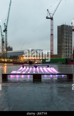 Rosa und Lila beleuchtete Brunnen in den Abend in der Kornkammer Square, King's Cross, London, UK, der Bahnhof und die Kräne im Hintergrund, 20. Stockfoto