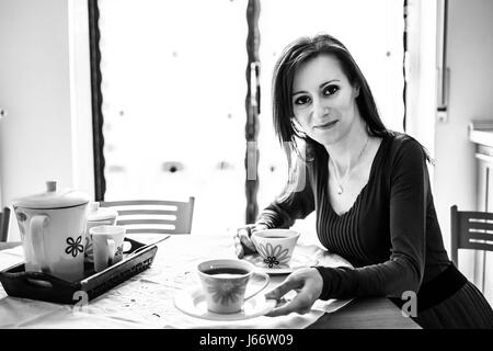Frau sitzt am Tisch mit einer Tasse Tee Stockfoto