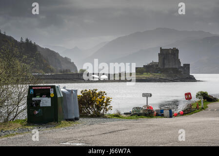 Eilean Donan Castle auf ein trüber Tag, gesehen von Dornie Gemeinschaft Halle Parkplatz mit recycling-Behälter, WC Schild und andere Ablenkungen im Vordergrund. Stockfoto