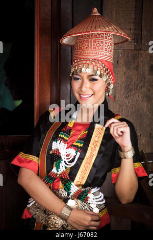 Schöne junge Bidayu Frau in ethnische Tracht der ethnischen Gruppe der Dayak. Posiert für die Kamera mit großen bunten Kopfschmuck in Borneo Stockfoto