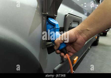 Netzteil für Ladestation für Elektroautos. Ladestation Elektroauto. Selektiven Fokus auf Hand, die Stromversorgung in einem Elektroauto wird eingesteckt Stockfoto