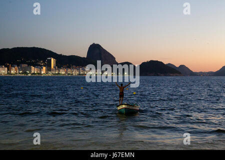 Fischer begrüßen die Sonne am frühen Morgen am Strand von Copacabana, Zuckerhut im Hintergrund, Rio De Janeiro, Brasilien Stockfoto