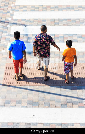 Mann mit zwei Jungen (Vater und Sohn) in kurzen Hosen auf einem Fußgänger im Sommer, von oben gesehen Stockfoto