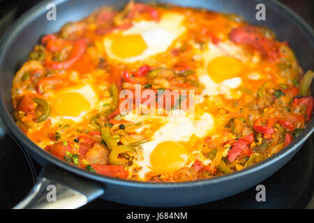Shakushuka eine herzhafte Ei Essen kochen in einer Pfanne erhitzen. Es enthält Paprika, Tomaten, Eiern, Zwiebeln und Gewürzen. Es ist eine orientalische Gericht. Stockfoto