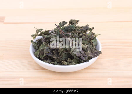Porzellanschüssel mit getrockneten Brennnesselblätter Stockfoto