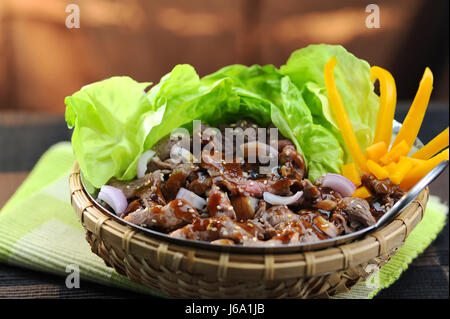 Rühren Sie gebratenes Rindfleisch mit Austern, Sauce und Salat im Bambuskorb Stockfoto