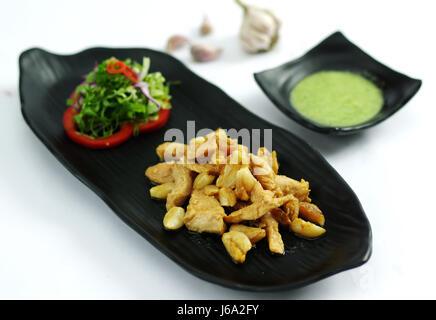 Ohne Knochen Grillhähnchen mit Knoblauch und Salat auf schwarzem Teller Stockfoto