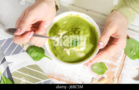 Junge Frau Hände mit grünen Spinash Suppe. Ansicht von oben Stockfoto
