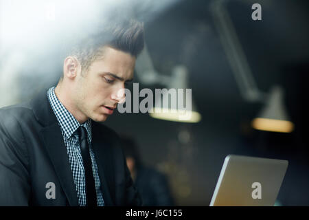 Seite Ansicht Porträt von hübscher junger Geschäftsmann mit Laptop im Büro, konzentrierte sich auf Arbeit Stockfoto
