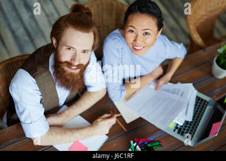 Hohen Winkel Porträt des modernen kreative Business-Team nach oben in die Kamera und lächelnd während der Arbeit im meeting Stockfoto