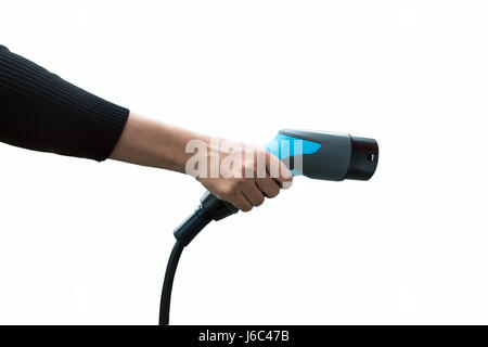 Hand, die Elektro-Auto-Ladegerät auf weißem Hintergrund. Luftverschmutzung und Gewächshaus-Gas-Emissionen-Konzept reduzieren. Stockfoto