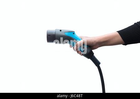 Hand, die Elektro-Auto-Ladegerät auf weißem Hintergrund. Luftverschmutzung und Gewächshaus-Gas-Emissionen-Konzept reduzieren. Stockfoto