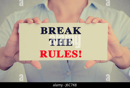 Closeup Geschäftsfrau Hände halten weiße Karte Schild mit Bruch die Regeln Textnachricht auf graue Wand Büro Hintergrund isoliert. Retro-Instagram Stil ich Stockfoto