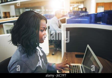 Seitenansicht des ziemlich afroamerikanischen jungen weiblichen Angestellten arbeiten am Laptop im Büro. Stockfoto