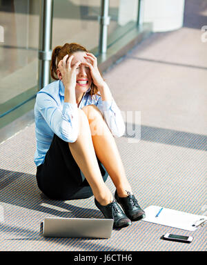 Closeup Portrait junge depressiv, traurig gestresst, Weinen Geschäftsfrau auf Boden in einem Saal des corporate building, Firmensitz, sitzend über ihre Fa Stockfoto