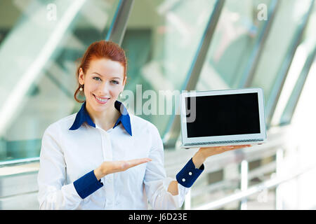 Closeup Portrait lächelnd Geschäftsfrau hält Laptop Notebook-Computer, zeigen etwas auf isolierte Bildschirmhintergrund Unternehmenszentrale Windows. Po Stockfoto