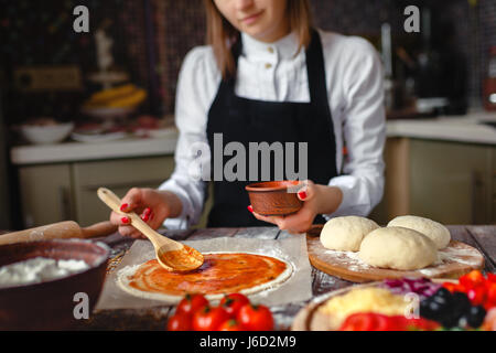 Gesichtslose Aufnahme Frau in weißem Hemd und Schürze der Teig während des Kochens beitragsfrei aufsetzen. Stockfoto