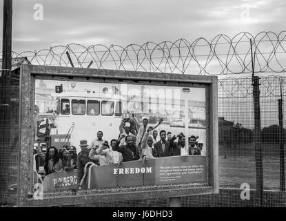 Schwarzweiß-Foto von Poster der letzten politischen Gefangenen von Robben Island in der Nähe von Stacheldraht beringt Gefängnis Eingang befreit zu werden, Kapstadt, Südafrika Stockfoto