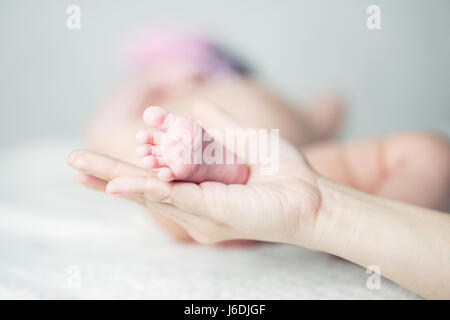 Nahaufnahme der Mutter Hand hält die Füße ihres Kindes Stockfoto